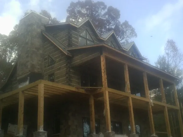 Stone chimney and dormers on a large log home with a timber porch in Collins